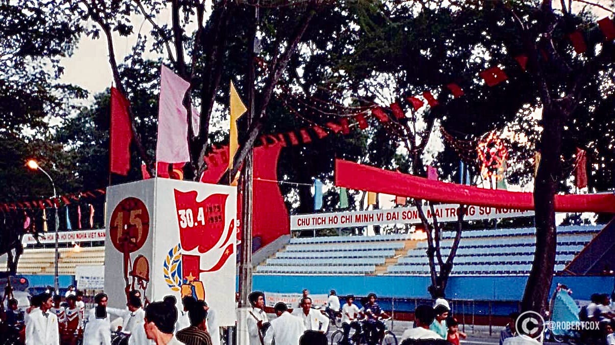 Parade rehearsals in front of bleachers on Nguyễn Huệ Boulevard, the banners say, “President Ho Chi Minh, the Great, Lives Forever in Our Cause.”
